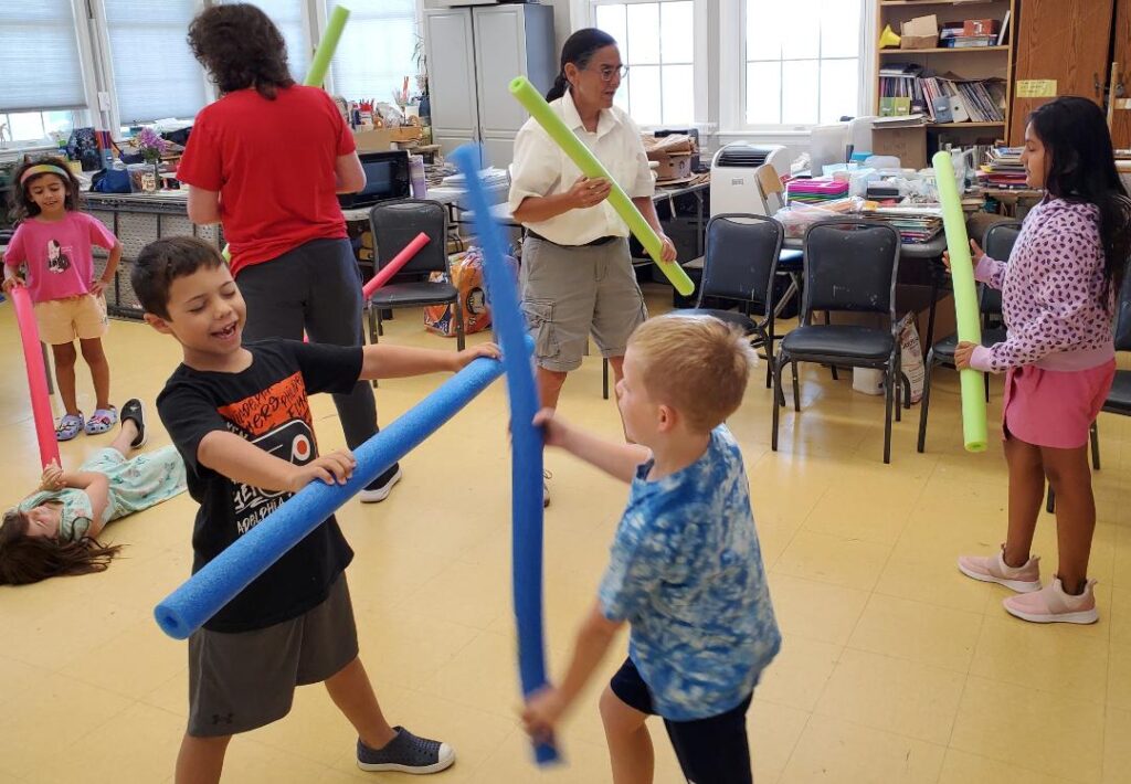 Kids playing with pool noodles outdoors